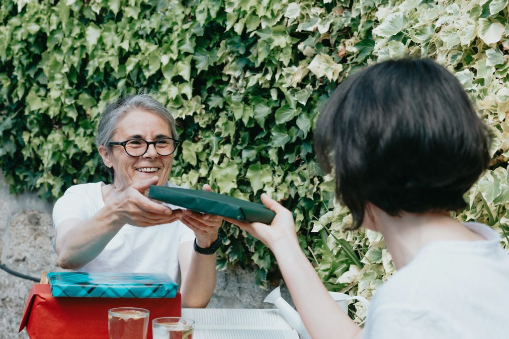 An older woman handing something to a woman