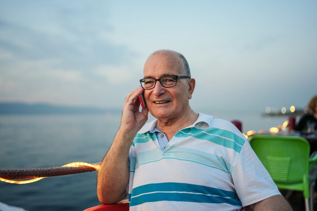 An old man wearing glasses talking on a phone