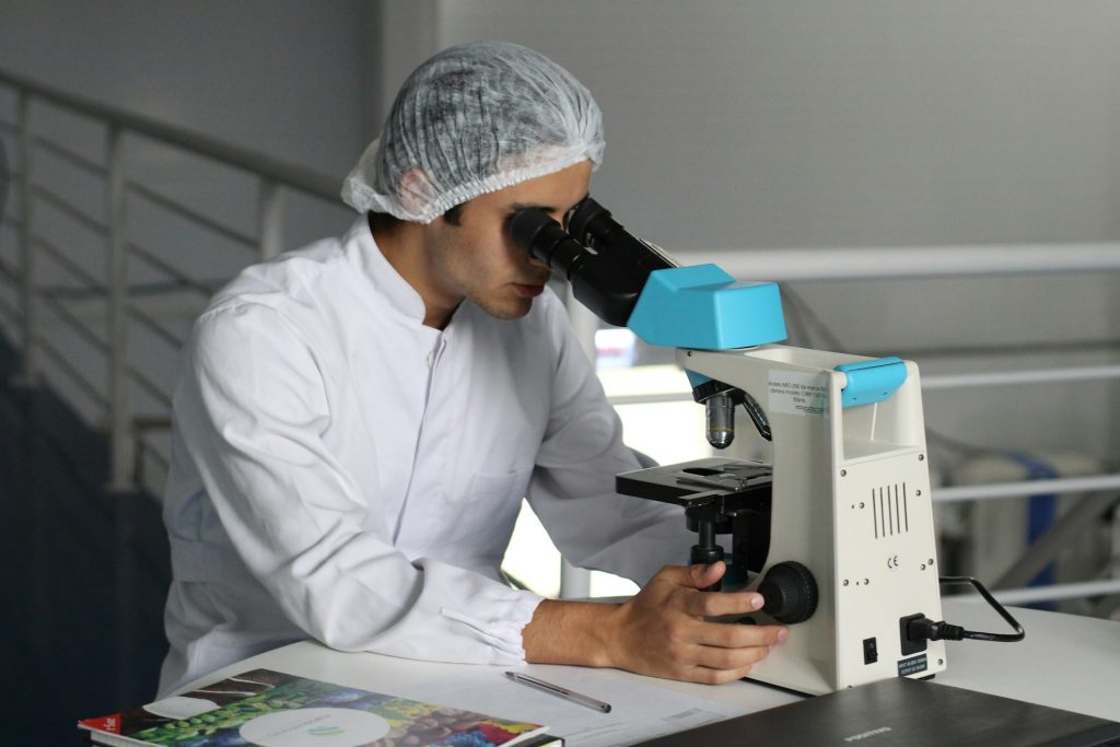 Man looking on a white microscope