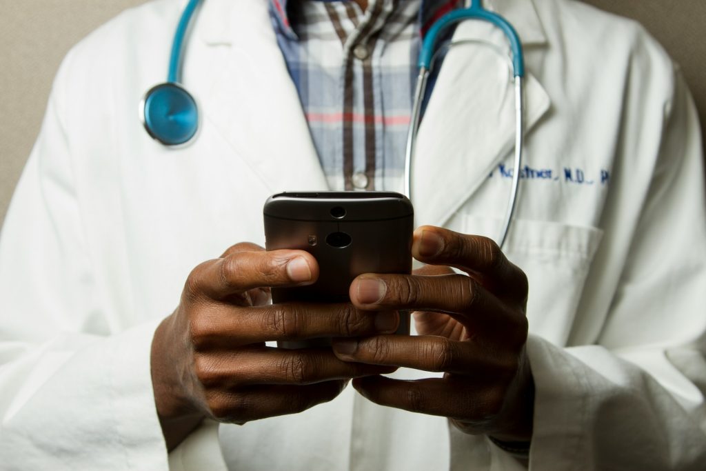 A man holding a phone with a lab gown