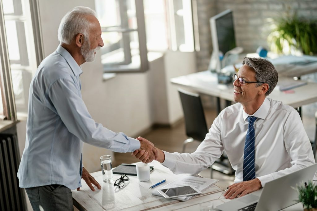 An older man shaking hands with another man